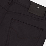 Close-up of the back pocket and waistband of the PESCAROLO Nerano M Cashmere Pants in a dark hue, highlighting intricate stitching details and a black leather patch adorned with embossed text and a small metallic emblem. This 5-pocket design exemplifies refined craftsmanship and premium quality, characteristic of pieces made in Italy.
