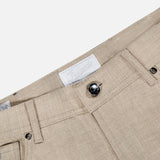 Close-up of the Nerano M Flannel Pants by PESCAROLO in beige cashmere, highlighting the waistband, dark button, belt loops, pockets, and a white fabric label with faint text. This stylish 5-pocket design provides both elegance and practicality.