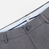 The Charlotte Performance Trouser Pant by PETER MILLAR features a gray stretch mélange fabric with a smooth, slightly textured finish for added comfort. Details include a single black button, belt loops, and a visible inner waistband label that reads PETER MILLAR.