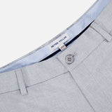 Close-up of PETER MILLAR Charlotte Performance Trouser Pant in light gray stretch mélange, featuring a button closure, belt loops, and blue-and-white striped inner waistband lining. Made with moisture-wicking fabric for all-day comfort.