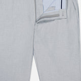 The Charlotte Performance Trouser Pant by PETER MILLAR features light gray stretch mélange fabric, partially open waistband and zipper showing a blue and white striped lining, belt loops, single button closure, and is crafted from recycled polyester.