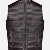 The PETER MILLAR Deerskin Leather Vest is a black, sleeveless, zip-front padded vest crafted from textured deerskin leather and lined with sumptuous merino wool, shown against a plain white background—a must-have luxury outerwear piece.