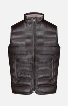 The PETER MILLAR Deerskin Leather Vest is a black, sleeveless, zip-front padded vest crafted from textured deerskin leather and lined with sumptuous merino wool, shown against a plain white background—a must-have luxury outerwear piece.
