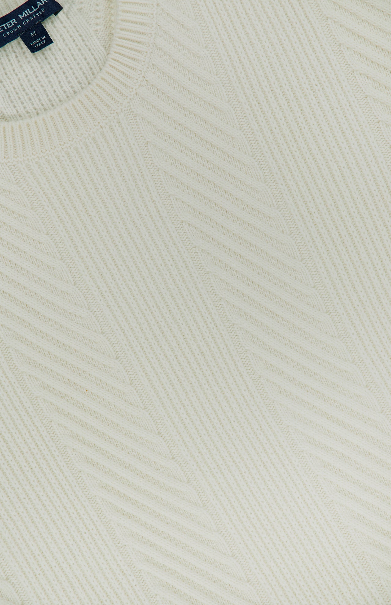Close-up of the Dolomite Crewneck Sweater, an off-white knit featuring ribbed patterns and a PETER MILLAR label near the collar.