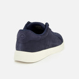 The PETER MILLAR Drift Classic Nubuck Sneaker for men features a navy upper with textured fabric, a white sole, and a small circular logo on the heel. Shown from the back left side against a plain white background.