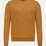 The Excursionist Flex Crewneck Sweater by PETER MILLAR is a long-sleeved, mustard yellow crew neck crafted from soft merino wool and shown against a white background—an ideal stylish travel sweater for any adventure.