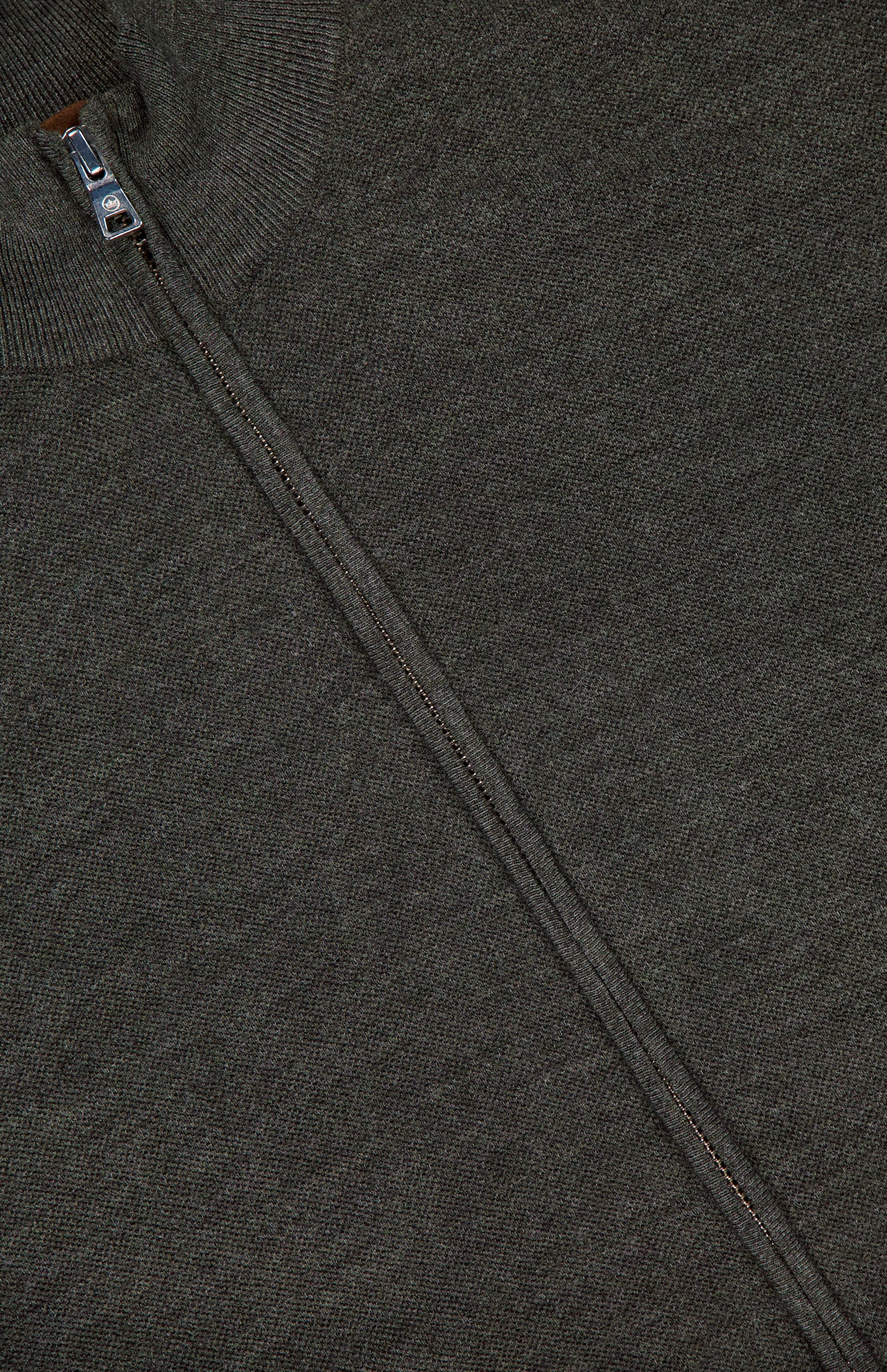 Close-up of the Excursionist Flex Full Zip Sweater by PETER MILLAR in dark gray textured knit merino wool, featuring a silver zipper running vertically from the collar.