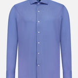 The PETER MILLAR Excursionist Flex Print Sport Shirt is a long-sleeved, button-up shirt in light blue, displayed on a plain white background. Crafted from wrinkle-resistant cotton-stretch fabric, this shirt features a classic collar and white buttons.