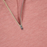 A close-up of the PETER MILLAR Excursionist Flex Quarter-Zip Sweater in salmon pink with a metal zipper and beige lining. Tags display “PETER MILLAR,” “M,” “Essentials,” and “Classic Fit”—ideal as a lightweight travel sweater.