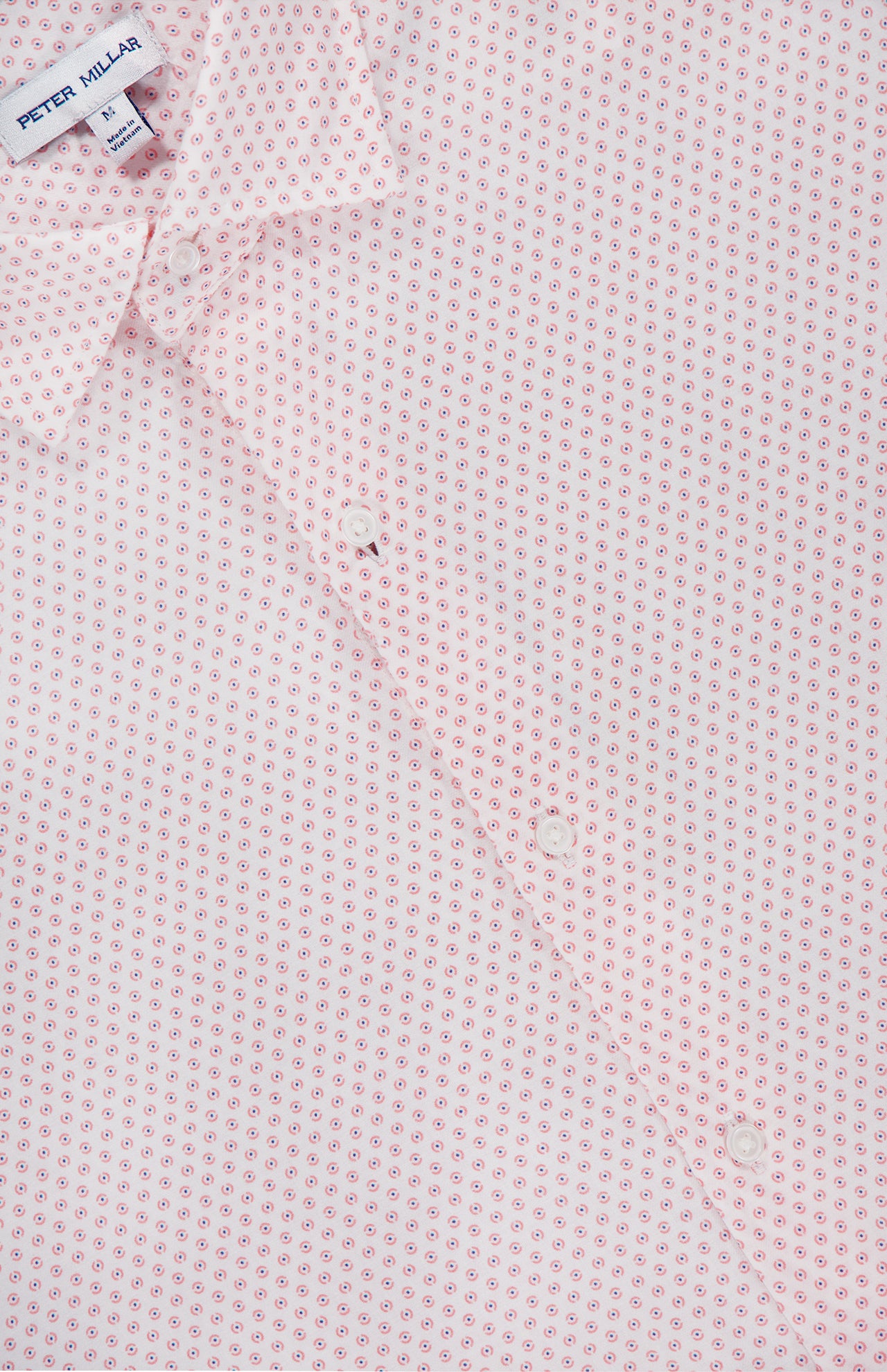 Close-up of the Tamarama Cotton Lyocell Sport Shirt by PETER MILLAR in light pink, showcasing a small red dot and circle graphic print. The stretch performance shirt’s label appears at the collar.