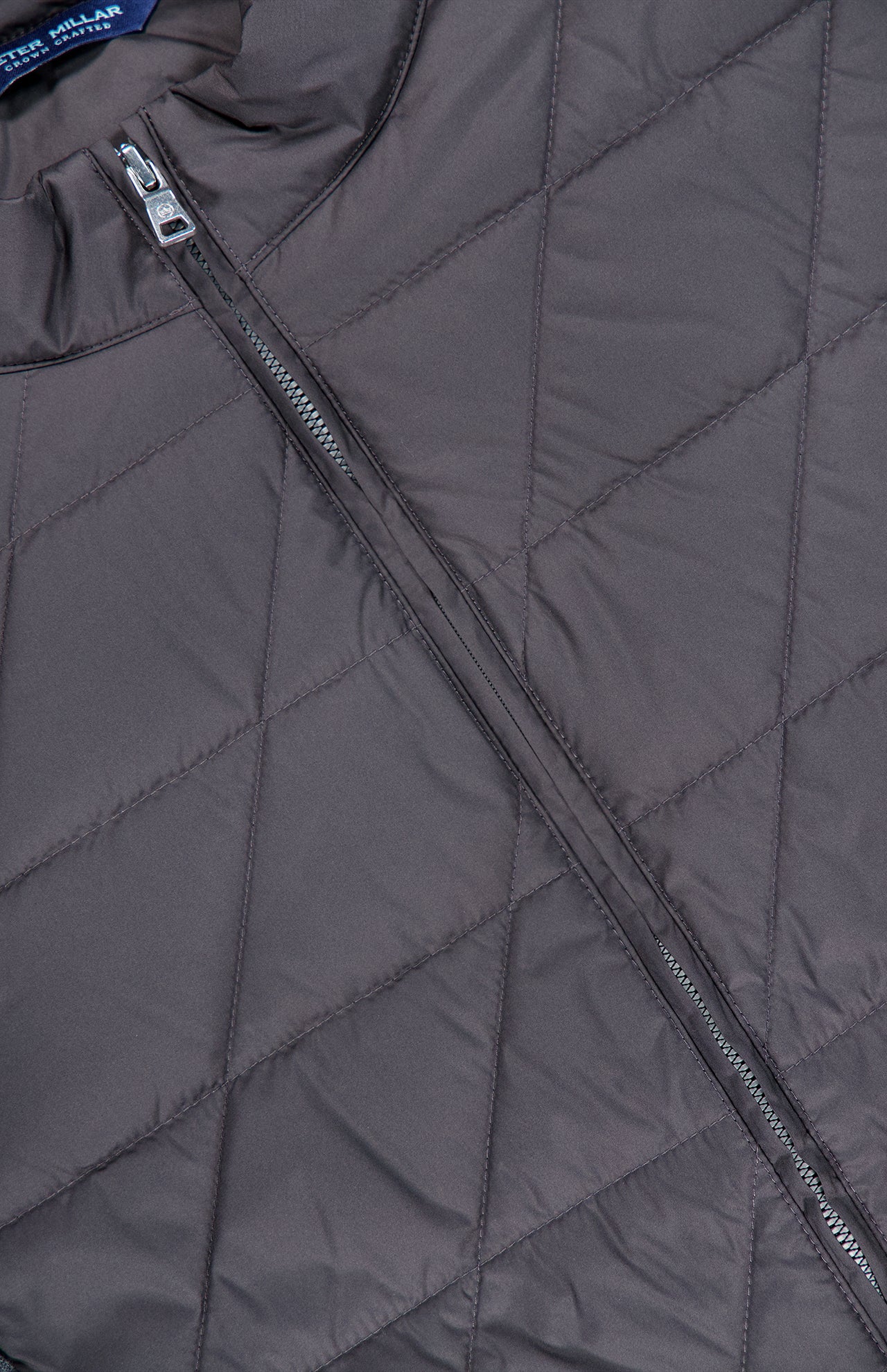 Close-up of the PETER MILLAR Walker Quilted Hybrid Jacket in dark grey, showcasing its diamond-pattern quilting and distinctive diagonal zipper. This water-resistant jacket blends style and practicality, making it an ideal choice for comfort in unpredictable weather.