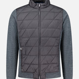 Introducing the Walker Quilted Hybrid Jacket from PETER MILLAR: A stylish dark grey jacket featuring a diamond quilted pattern on the main body, complemented by lighter textured gray sleeves and hem. Designed with a high collar, front zipper, and convenient side pockets, this jacket is both wind resistant and water resistant—delivering exceptional comfort and protection for changing weather conditions.