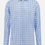 The PETER MILLAR Waterrock Cotton Lyocell Sport Shirt features long sleeves and a blue, light blue, white, and grey plaid pattern with stretch performance, displayed on a plain white background.