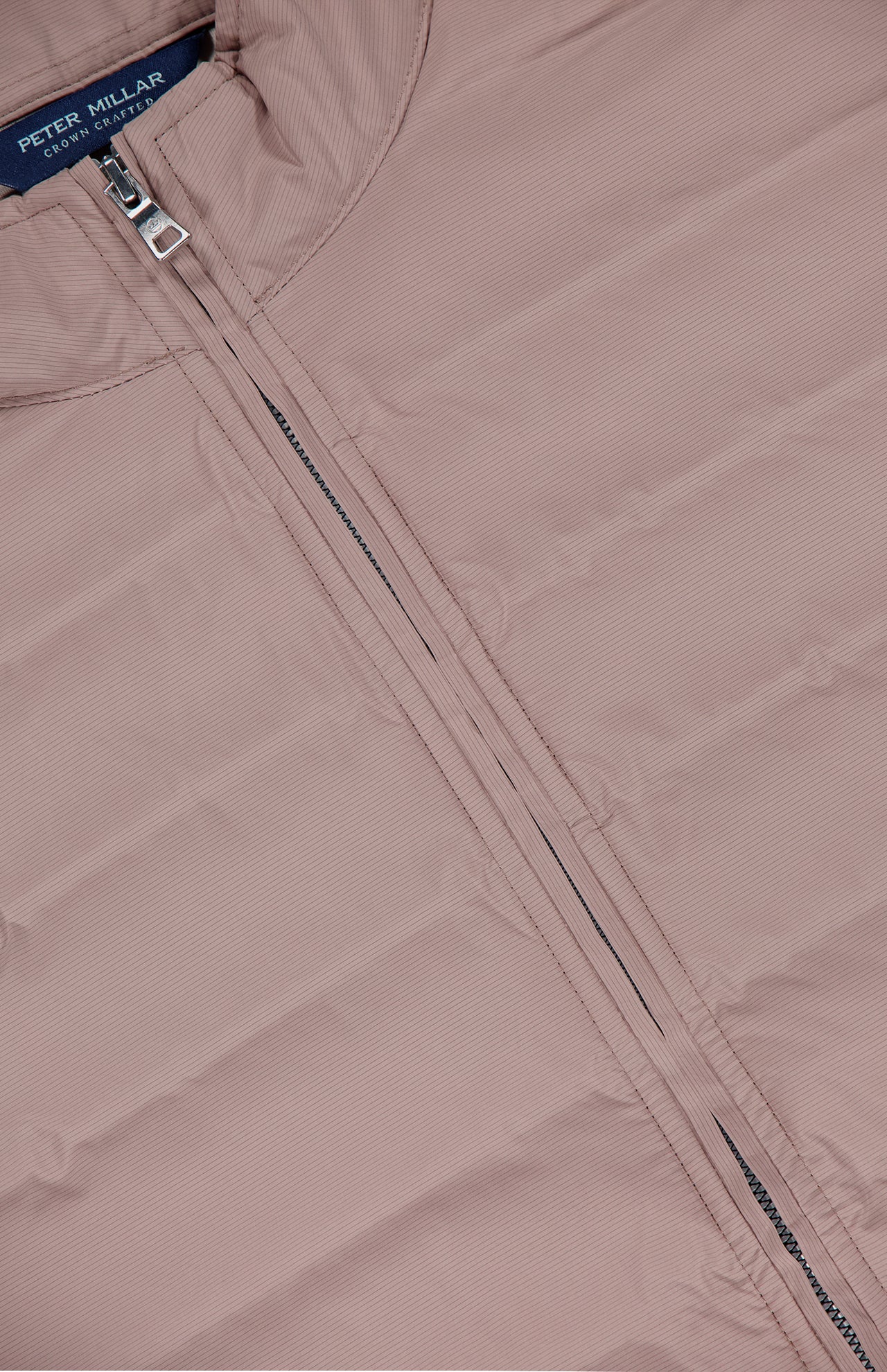 Close-up of a light mauve Winsome Hybrid Jacket by PETER MILLAR, featuring a visible front zipper and small collar.