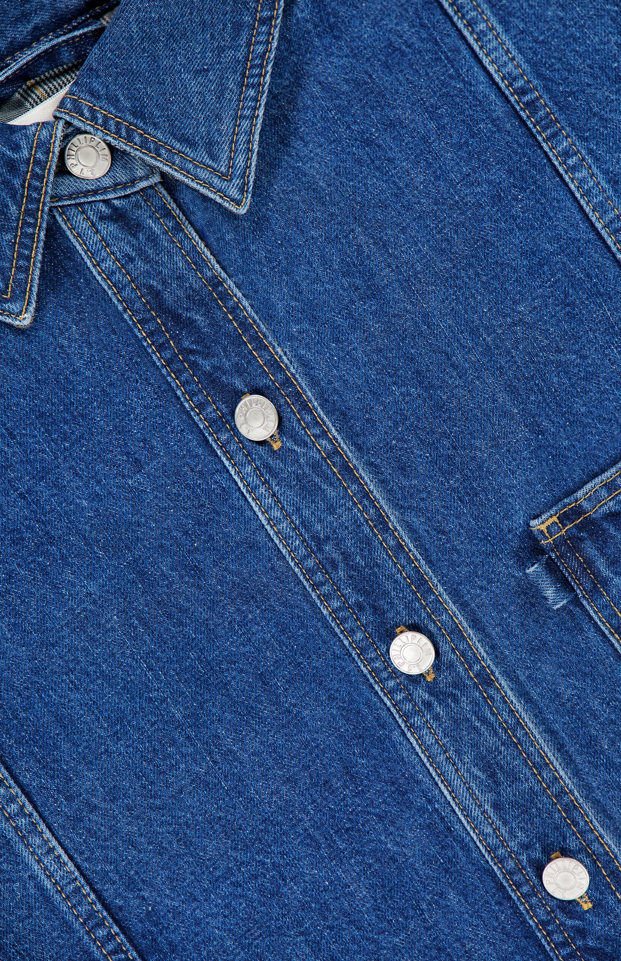 Close-up of the 3.1 PHILLIP LIM Oversized Denim Shirt Jacket in blue, highlighting metal buttons, yellow stitching, a collar, and part of the chest pocket. The fabric texture and detailed stitching are clearly visible.