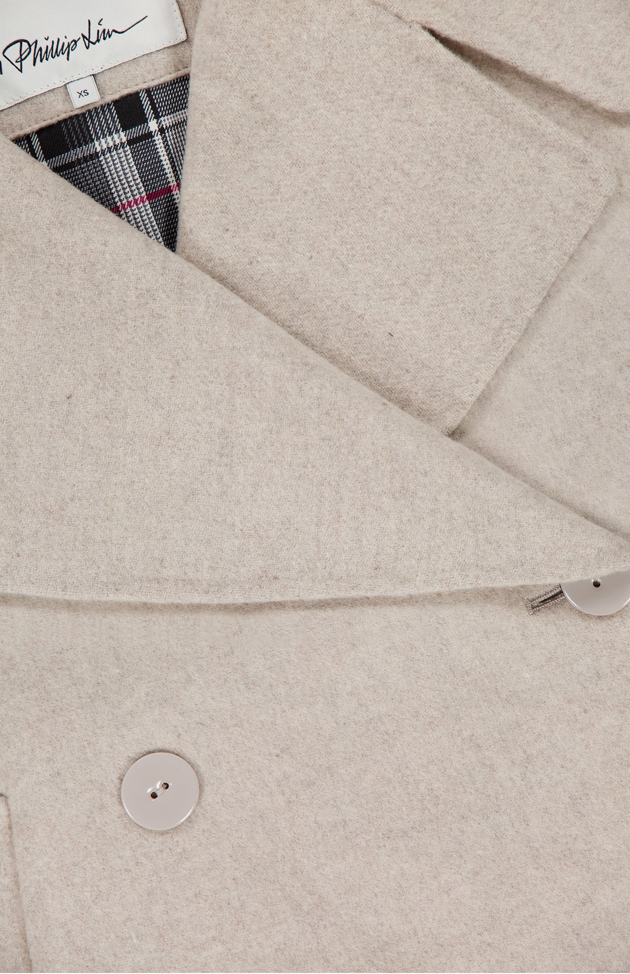 Close-up of the 3.1 PHILLIP LIM Recycled Wool Peacoat with Plaid Combo in beige, featuring large lapels, two beige buttons, plaid lining at the collar, and a visible brand label on the inner neckline.