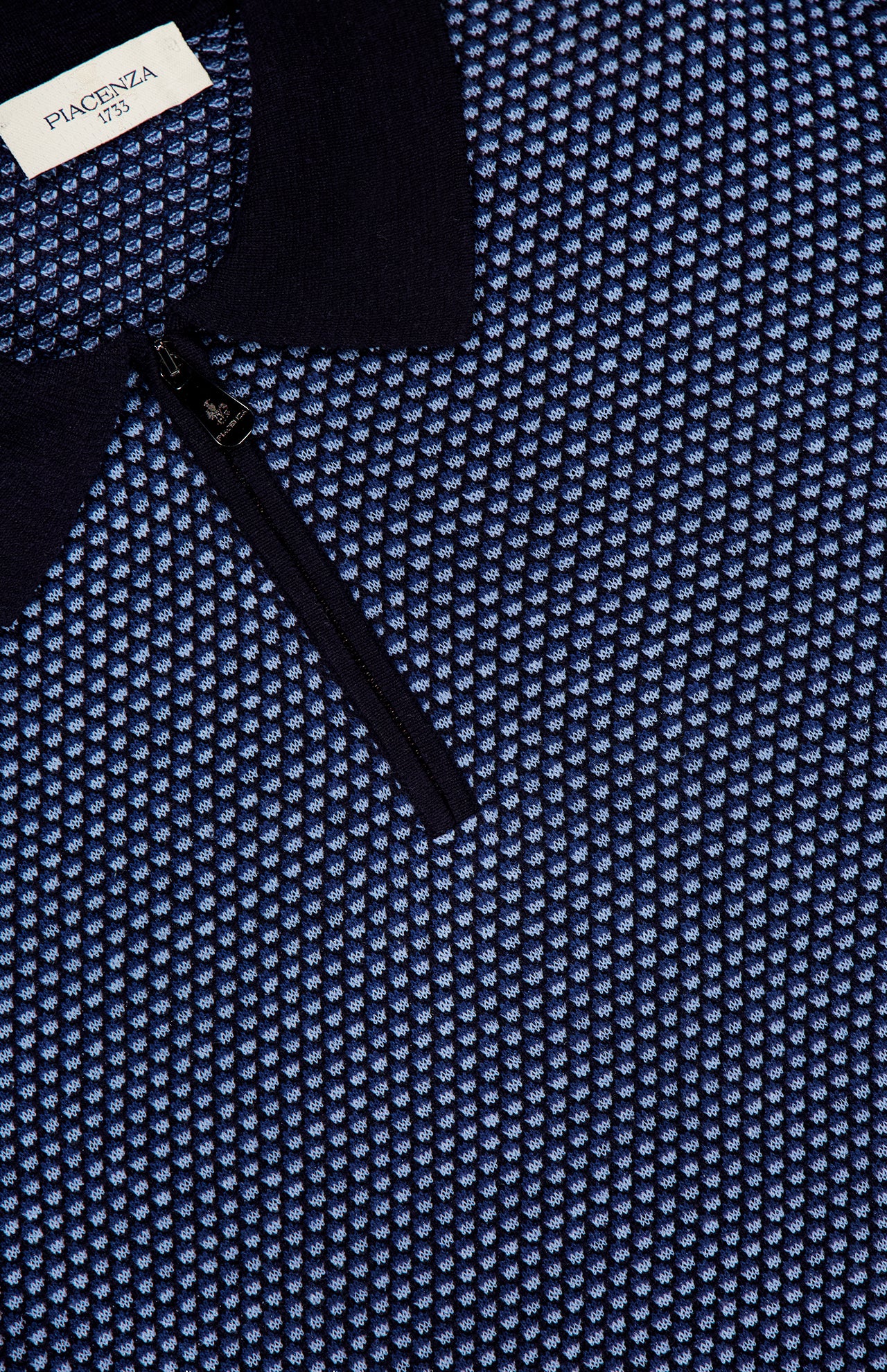 Close-up of a textured blue and navy PIACENZA 1/4 Zip Knit Polo Shirt featuring a black zipper and collar, with the PIACENZA label visible near the collar.