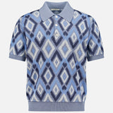 The PIACENZA Diamond Shaped Print Knit Polo Shirt features a short-sleeve design with a blue, white, and navy geometric diamond pattern, ribbed collar, cuffs, and hem, and a three-button placket. Expertly made in Italy.