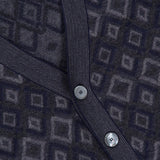 Close-up of the PIACENZA Icon Argyle Stitch Cardigan, featuring a dark geometric pattern. A ribbed band with three round, silver buttons runs diagonally across the fabric.