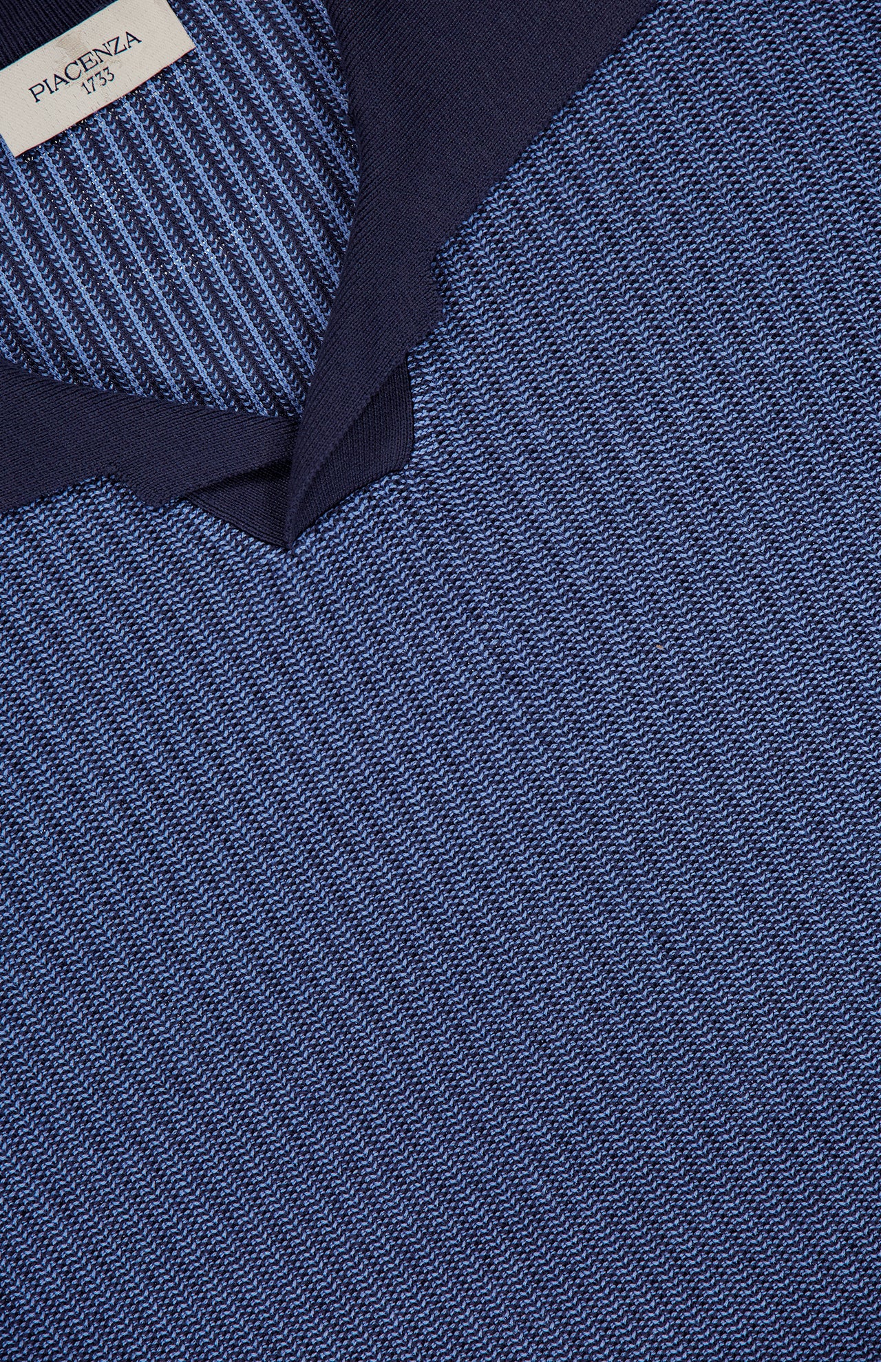 Close-up of the Sailor Johnny Collar Polo Sweater by PIACENZA, featuring textured blue silk cotton fabric with alternating fine and thick stripes for an elegant look; the label reads PIACENZA.