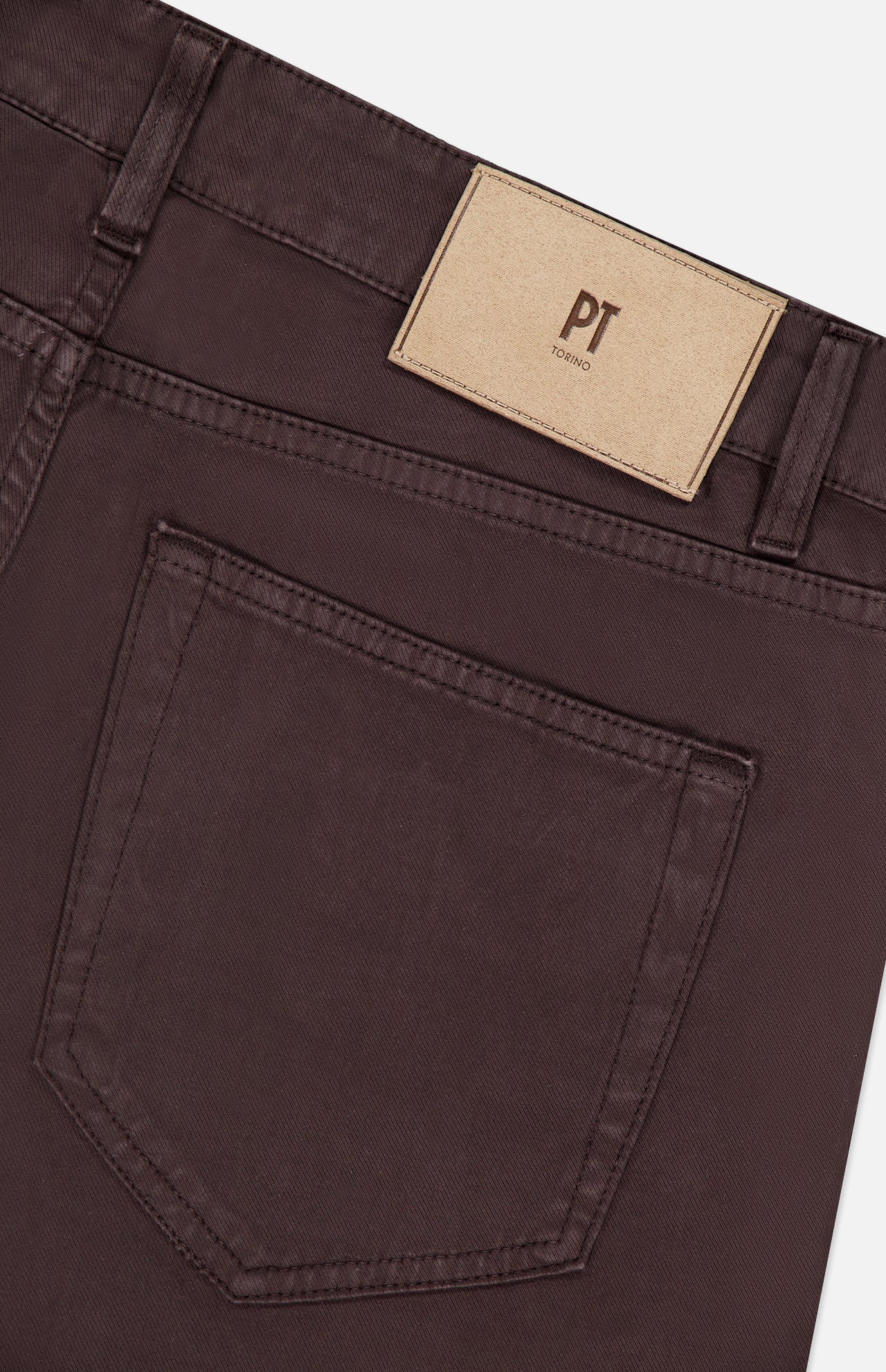 Close-up of the back pocket and waistband of PT TORINO Stretch Jeans in Testa Di Moro, featuring a beige label with the brand name above the pocket. The fabric, a cotton cashmere blend, gives these men's designer jeans a refined and soft texture.
