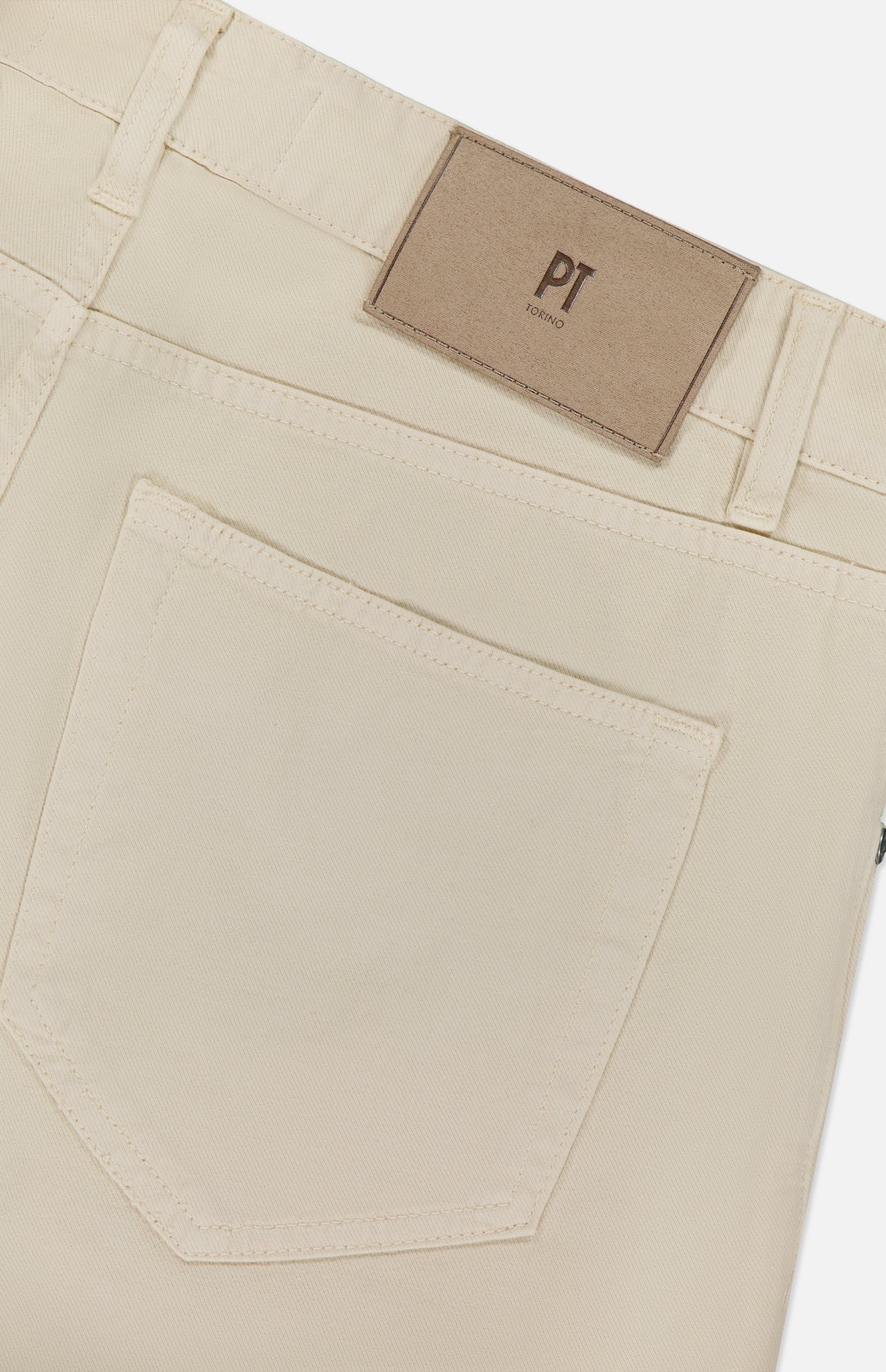 Close-up of the back pocket and waistband of the Cotton & Cashmere Stretch Tricotine Jeans in Stone by PT TORINO, featuring a brown rectangular leather patch with the brand’s logo above the pocket. Expertly crafted in Italy, these jeans combine cotton and cashmere for exceptional comfort and showcase a refined 5-pocket design that offers timeless style.