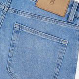 Close-up of the back pocket of PT TORINO Denim Stretch Jeans in light blue, with a brown leather patch on the waistband bearing the PT TORINO logo, highlighting a classic vintage style.