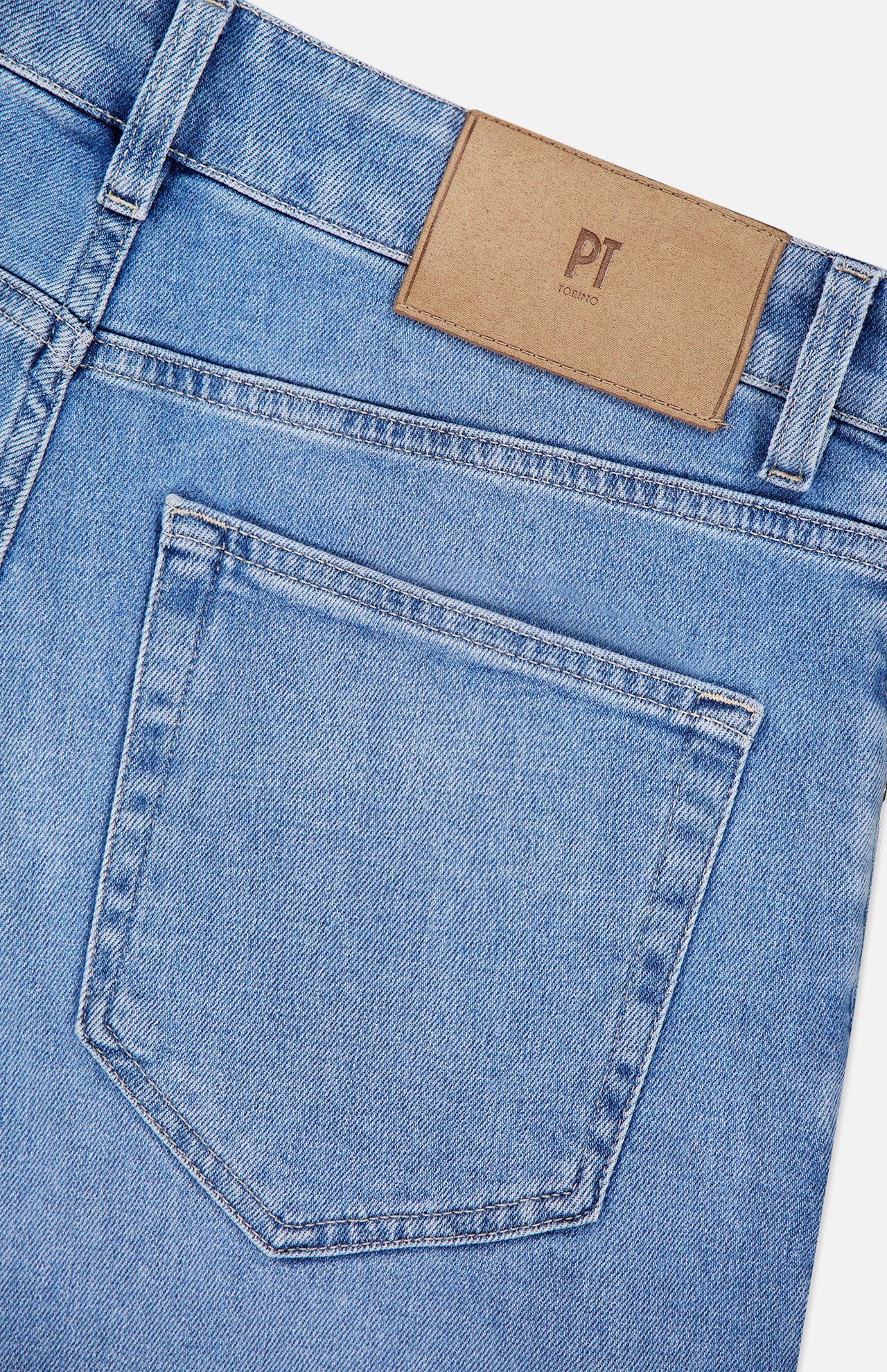 Close-up of the back pocket of PT TORINO Denim Stretch Jeans in light blue, with a brown leather patch on the waistband bearing the PT TORINO logo, highlighting a classic vintage style.
