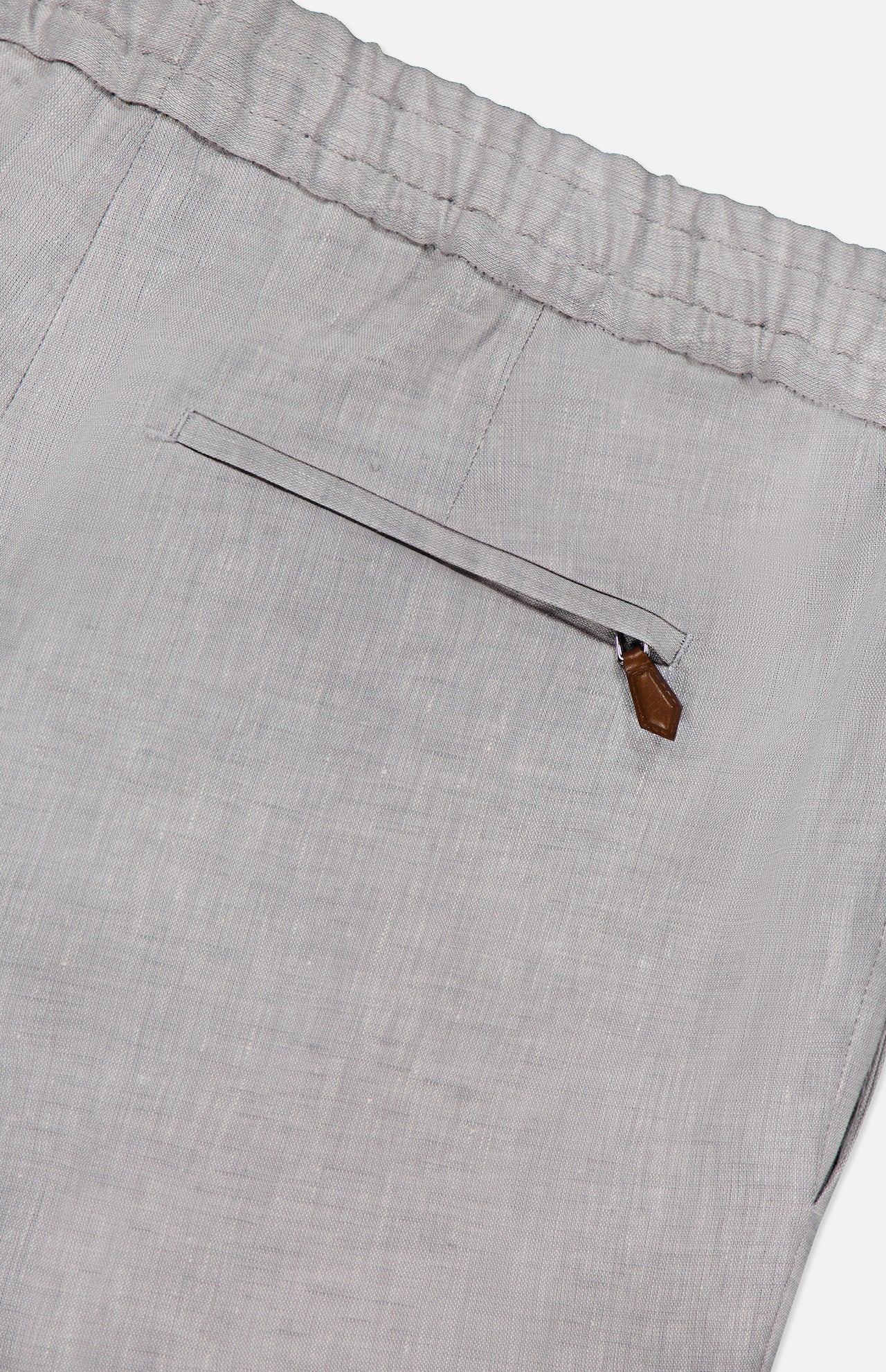 The PT TORINO Linen Comfort Jogger is a light gray men's pant with a textured linen fabric, elastic waistband, single zippered back pocket with brown pull tab, blending comfort and style.