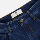 Close-up of the waistband and upper section of Stretch Japan Denim Jeans by PT TORINO in dark blue with contrast stitching, silver button, belt loops, and a white PT label.