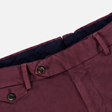 Close-up of the waistband and upper section of the PT TORINO Stretch Overdyed Solaro Trouser Pant in burgundy, featuring belt loops, buttons, and a partial view of the front pocket against a light background—a refined option for professional attire.