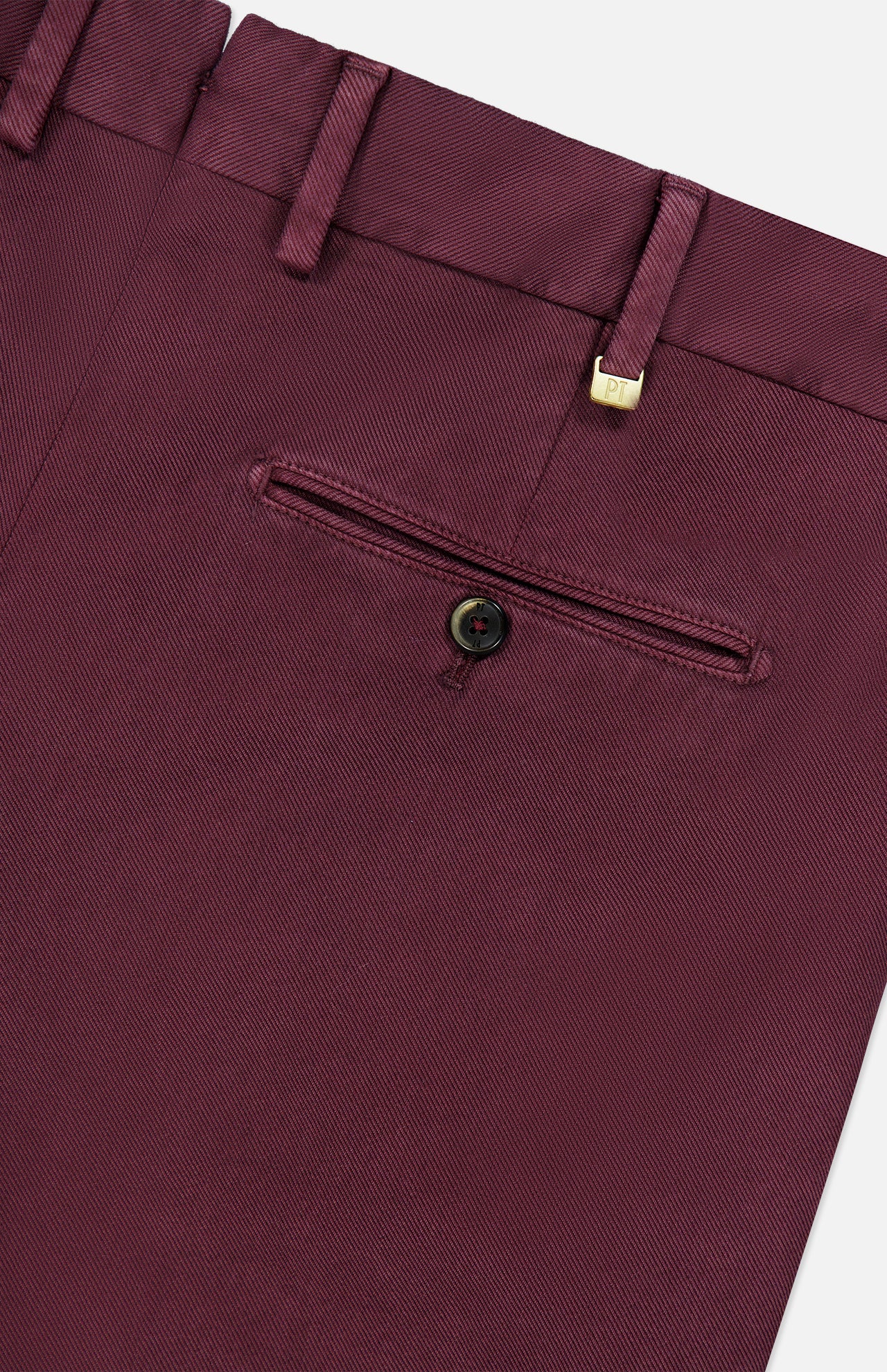 Close-up of the Stretch Overdyed Solaro Trouser Pant by PT TORINO in burgundy, showcasing a back pocket with a single button and a gold metal accent near the waistband. Crafted from a cotton-blend fabric with a subtle diagonal texture, these trousers are an ideal option for professional attire.