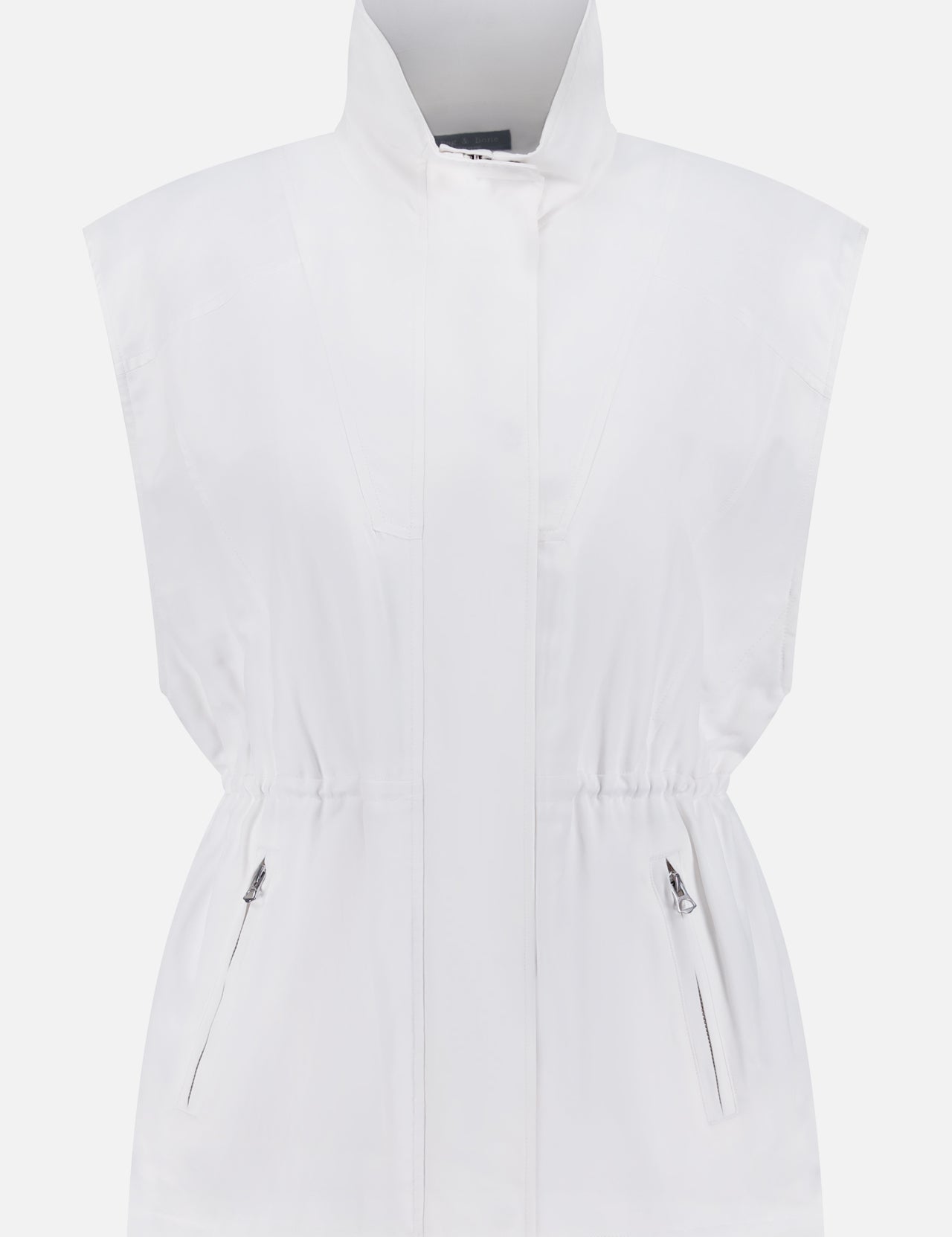 The Monica Oversized Cinch Vest by RAG & BONE is a sleeveless white vest with a high collar, zip and snap closure, cinched waist, and two zippered front pockets, shown against a plain white background.
