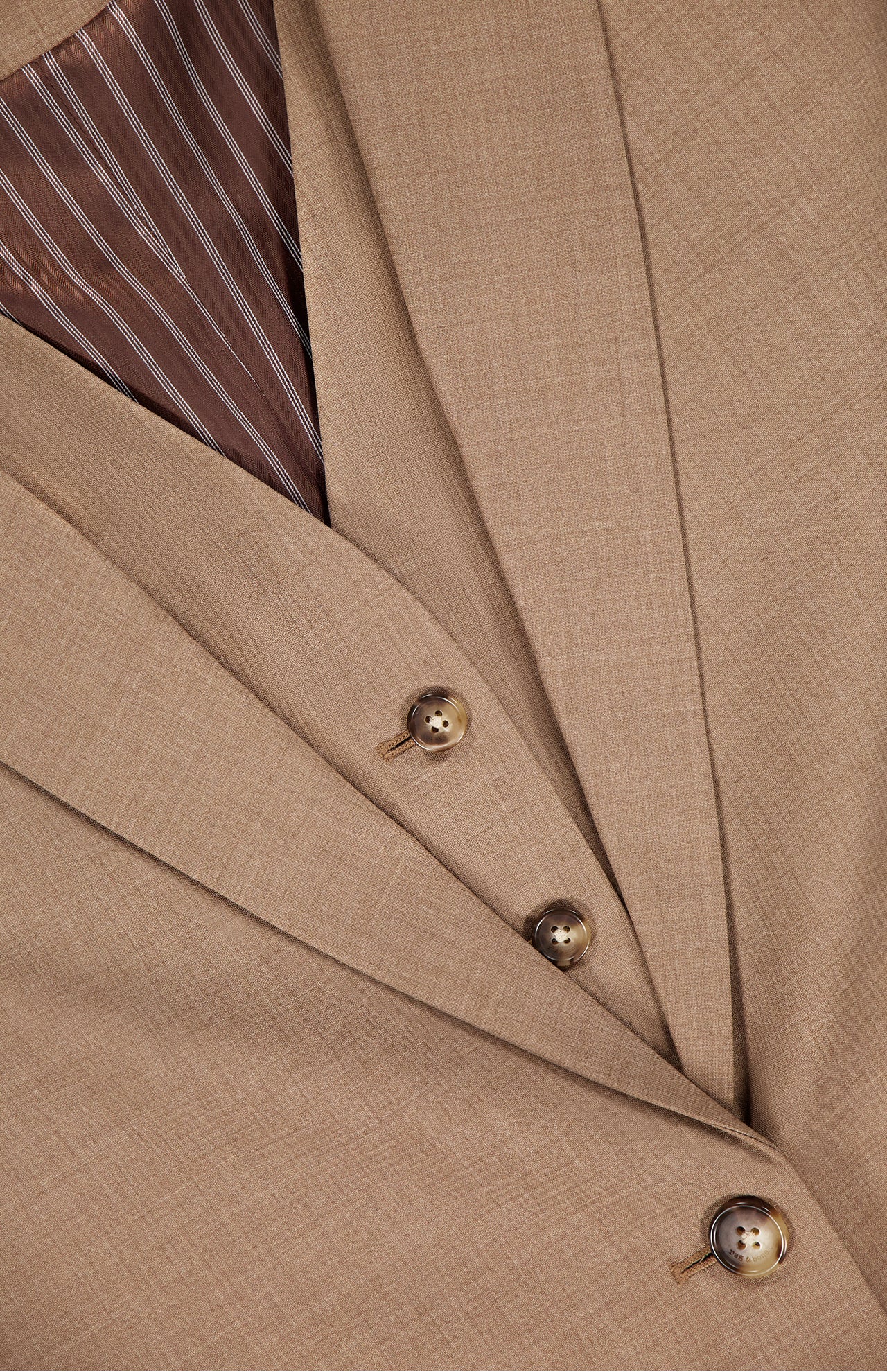 Close-up of the RAG & BONE Jennifer Combo Blazer in tan wool blend, featuring three brown buttons, overlapping lapels, and a brown-and-white striped inner lining.