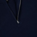 Close-up of the Danton Cotton Quarter Zip Sweater by RAG & BONE in navy, featuring a textured knit and a silver half-zipper partially unzipped with a black label visible inside the collar.