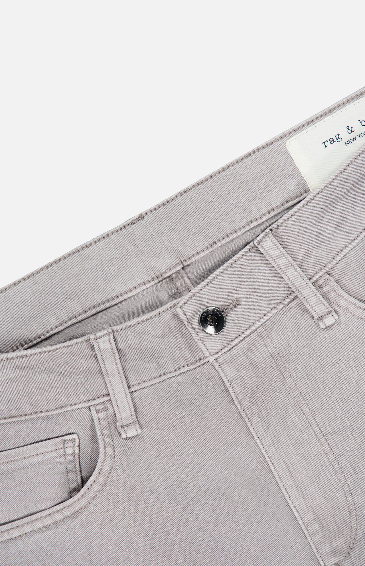 Close-up of the waistband and upper section of the RAG & BONE Fit 3 Aero Stretch Pant in light grey, showcasing Aero Stretch technology, a black button, belt loops, and a partially visible label inside the waistband.