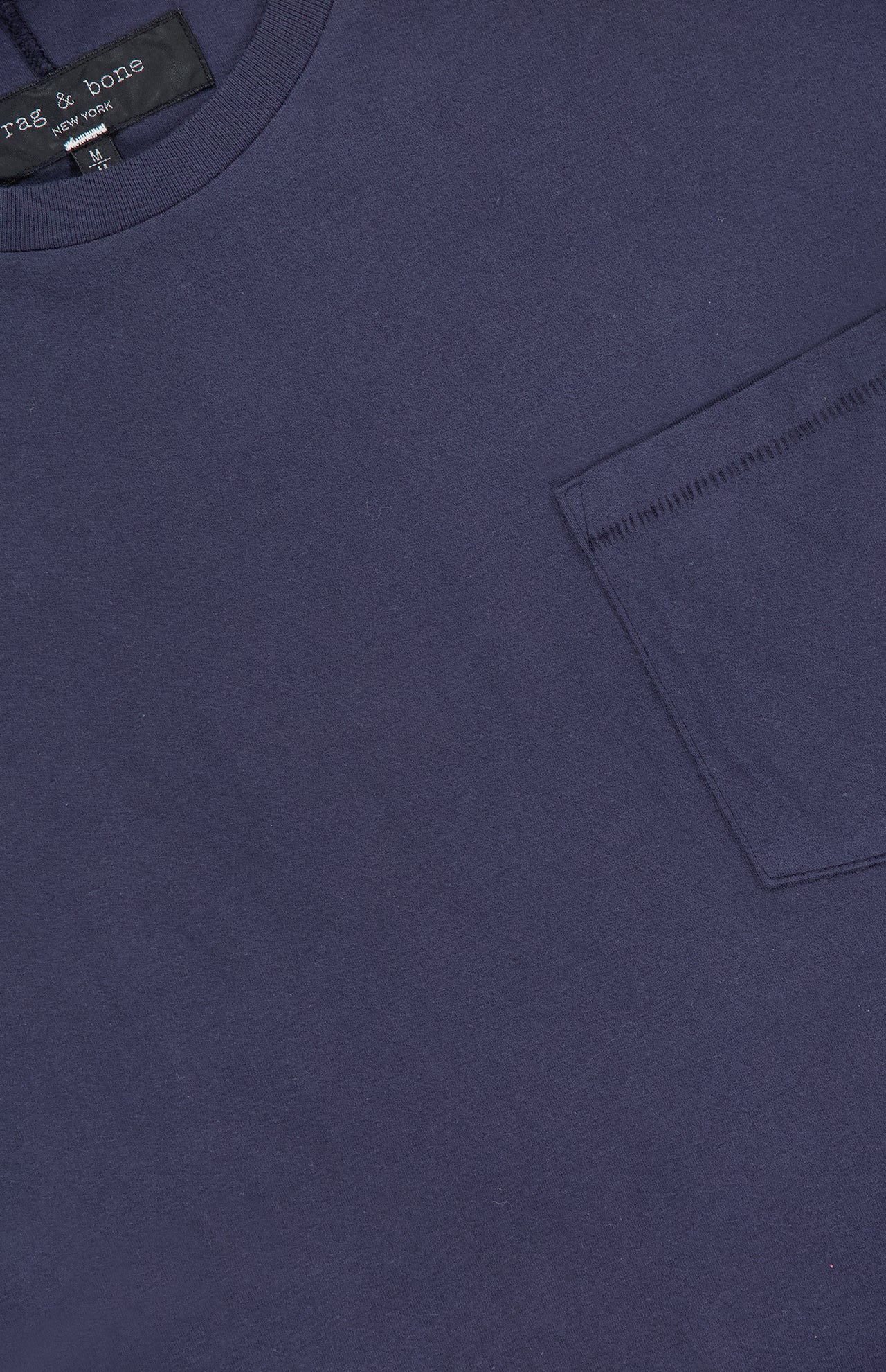 Close-up of the RAG & BONE Garment Dye Classic Pocket T-shirt in navy, featuring a right chest pocket, visible collar, and a label at the top left of this men's casual shirt.