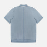 The Harvey Rib Polo Shirt by RAG & BONE is shown from the back in light blue-grey, featuring a retro stitch-textured pattern, ribbed hem and cuffs, and a flat collar with a subtle white stripe for vintage appeal.