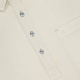 Close-up of RAG & BONE Popover Long Sleeve Shirt in cream cotton, featuring a partial button placket with four silver buttons, right chest pocket, visible white stitching, and a label that reads rag & bone NEW YORK for a minimalist design.