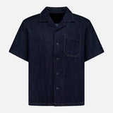The RAG & BONE Resort Denim Shirt is a short-sleeved, dark blue featherweight denim camp shirt with a button-up front, notched collar, single chest pocket, and tan stitching, shown against a plain white background.
