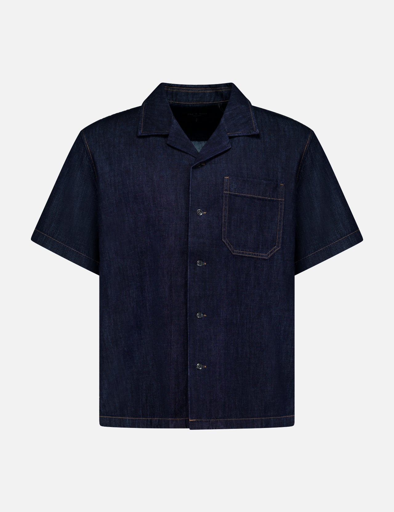 The RAG & BONE Resort Denim Shirt is a short-sleeved, dark blue featherweight denim camp shirt with a button-up front, notched collar, single chest pocket, and tan stitching, shown against a plain white background.
