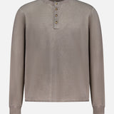 The RAG & BONE Washed Cotton Henley Shirt is a taupe, long-sleeve top with a round neck, four-button placket, cuffed wrists, and a loose fit. Made from cotton yarn, it features a subtle sunfaded look and simple design.