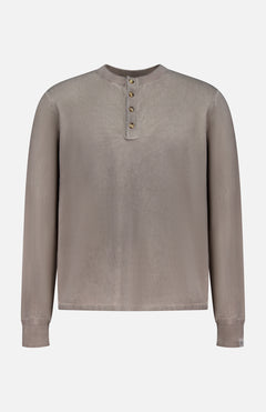 The RAG & BONE Washed Cotton Henley Shirt is a taupe, long-sleeve top with a round neck, four-button placket, cuffed wrists, and a loose fit. Made from cotton yarn, it features a subtle sunfaded look and simple design.