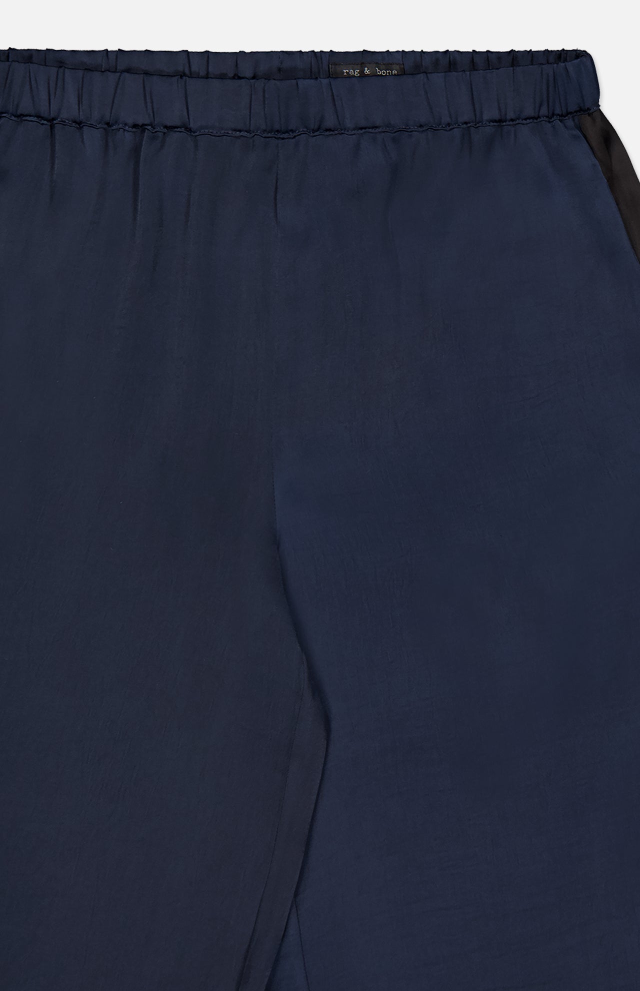 Close-up of the Olivia Contrast Stripe Pant by RAG & BONE, featuring a relaxed fit, navy hue, elastic waistband, subtle stitching, and a smooth, slightly shiny silk texture.