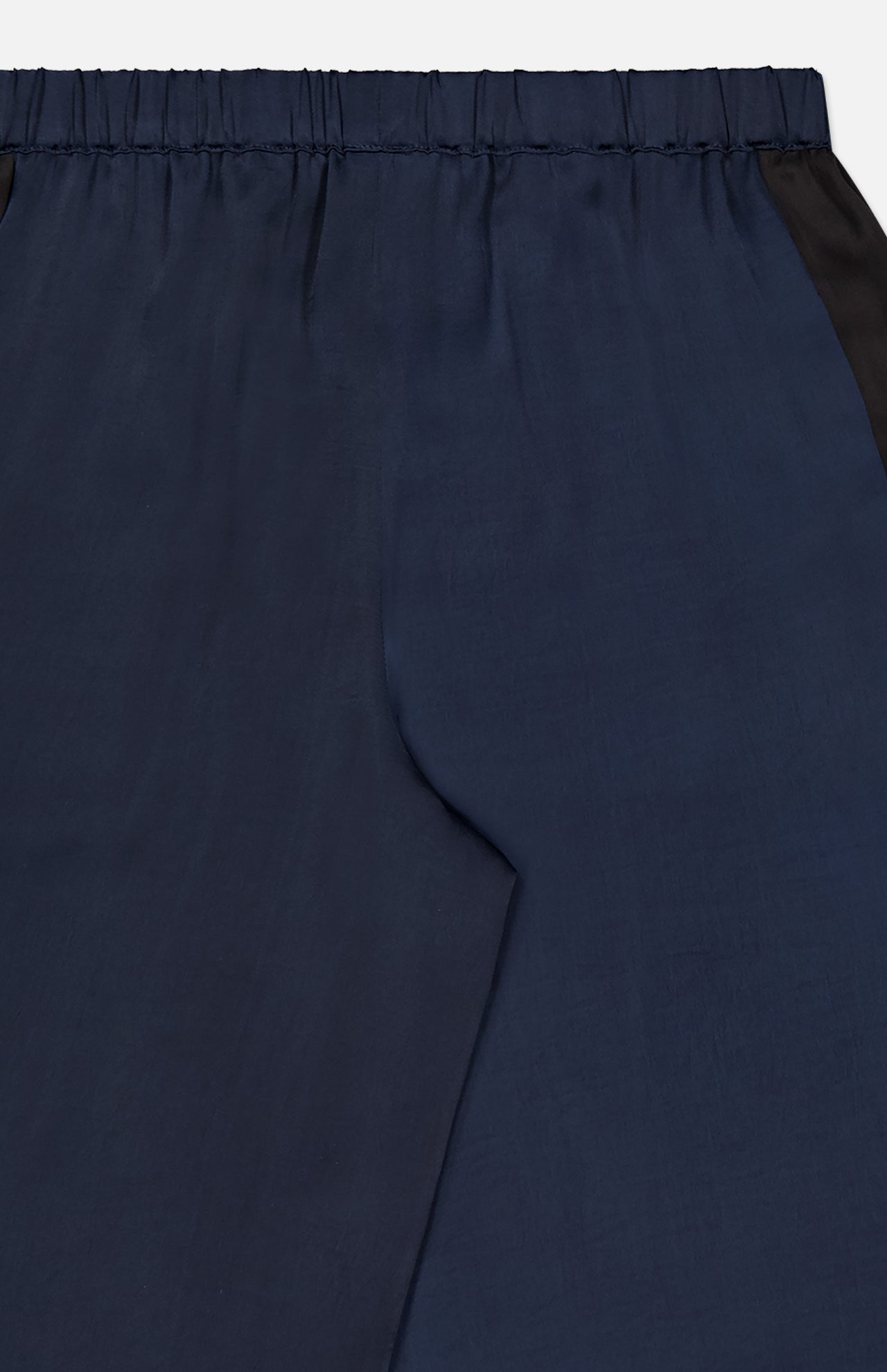 Close-up of the Olivia Contrast Stripe Pant by RAG & BONE, featuring a relaxed fit, elastic waistband, and black side panels for a sleek, minimal look with smooth navy fabric.
