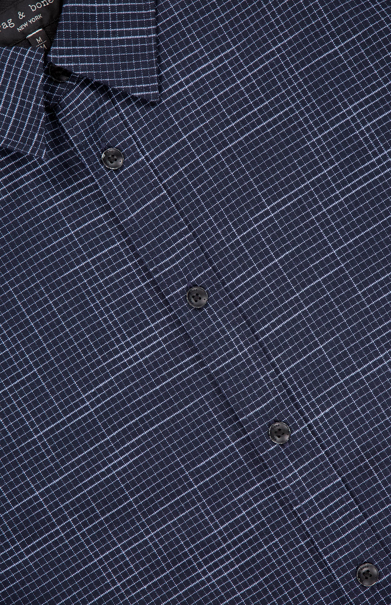 Close-up of the Tomlin Crosshatch Pattern Shirt by RAG & BONE, a navy modern fit with thin white grid lines, three black buttons, and part of the collar for a sharp, contemporary look.