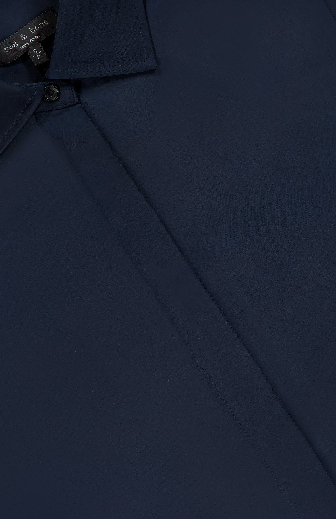 Close-up of the Venus Popover Removable Cami Blouse by RAG & BONE in dark navy, featuring a hidden button placket and smooth, satin-like fabric. Brand tag is visible at the neckline.