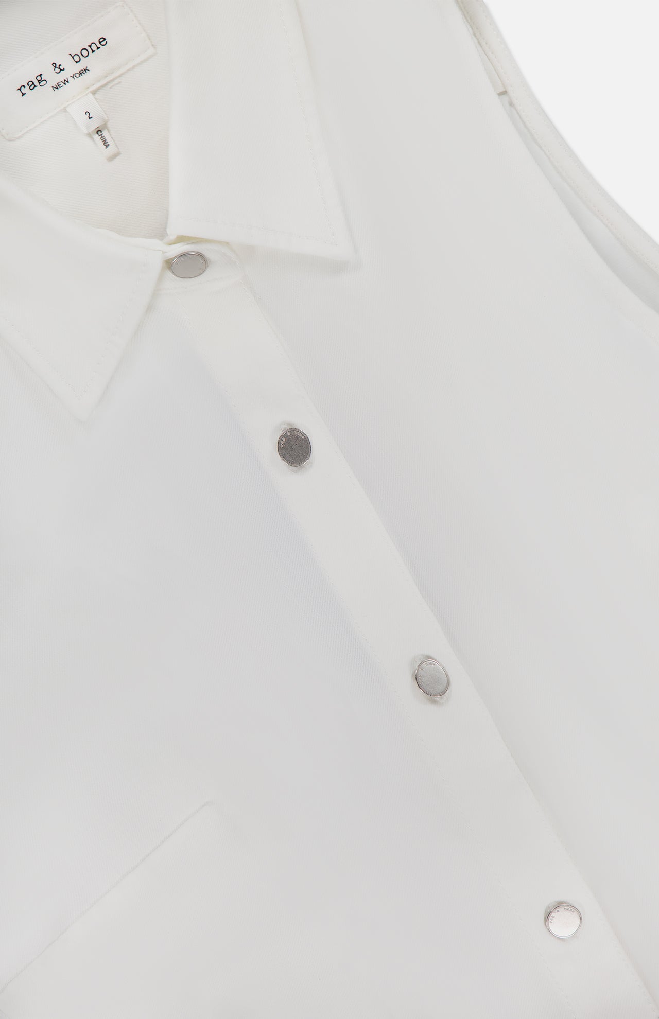 Close-up of the Airflex Leah Ruched Side Tank Top by RAG & BONE, featuring a white sleeveless design with subtle side ruching and the rag & bone brand label inside the neckline.