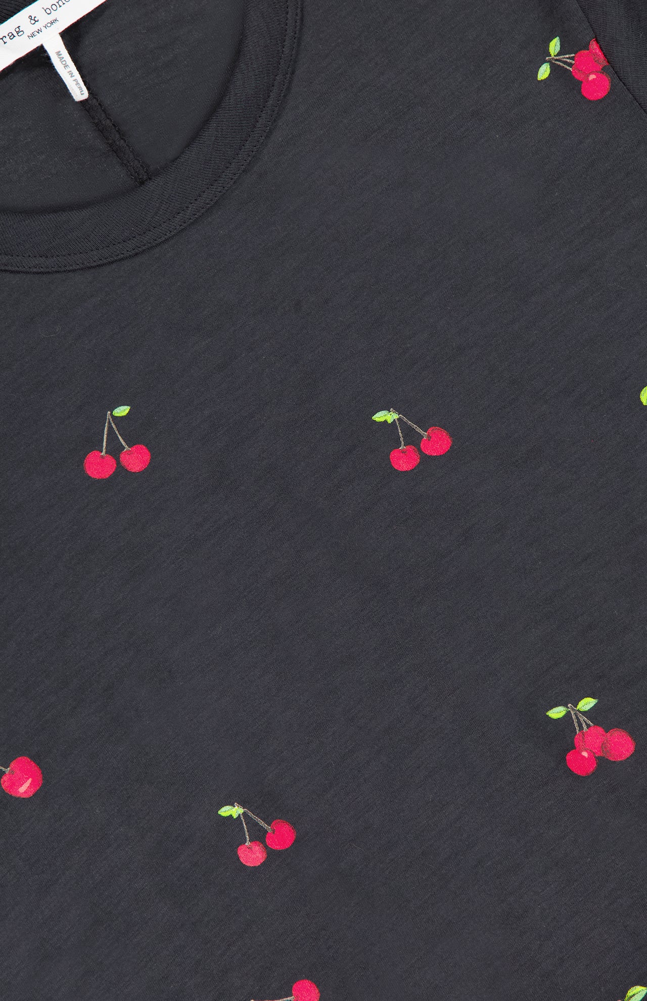 The All Over Cherry T-shirt by RAG & BONE features a playful black cherry print with red cherries and green stems, crafted from soft Peruvian cotton for comfort and style.