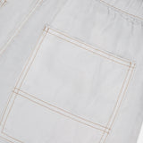 Close-up of the RAG & BONE Atlas Drawcord Linen Pant, featuring a white linen fabric, elastic waistband, and a large square pocket with visible tan stitching in a rectangular pattern. High-rise design adds to its modern look.